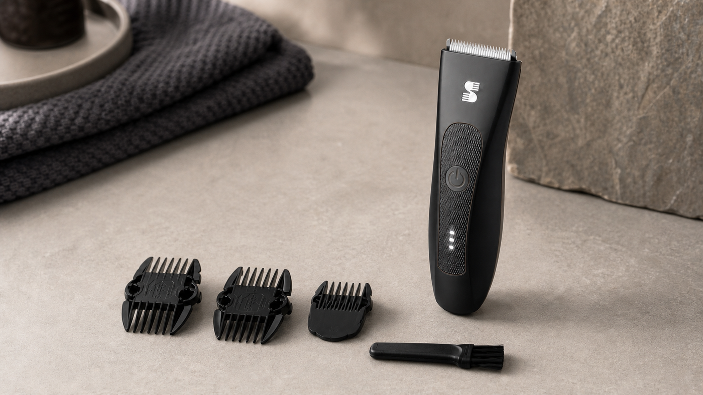 Black MANSPOT body groomer with three guide-comb pieces and a cleaning brush arranged on a warm stone counter