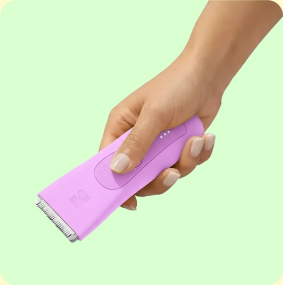 Hand holding a pink LADYSPOT body trimmer for women's grooming