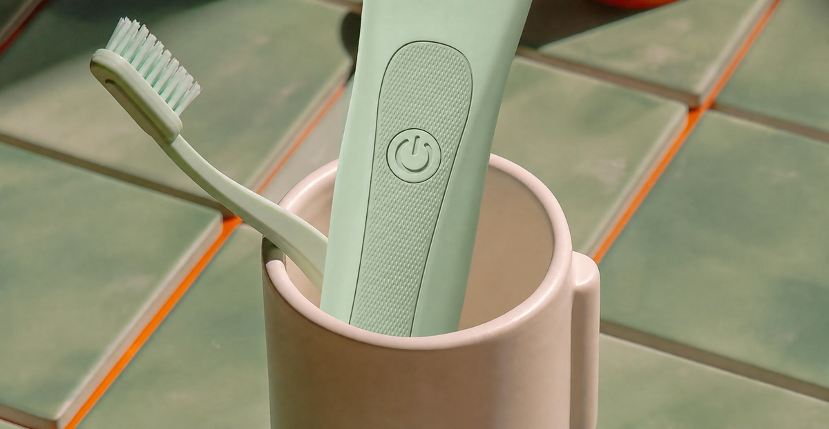 Mint green electric toothbrush and manual toothbrush in a bathroom cup with no colored light