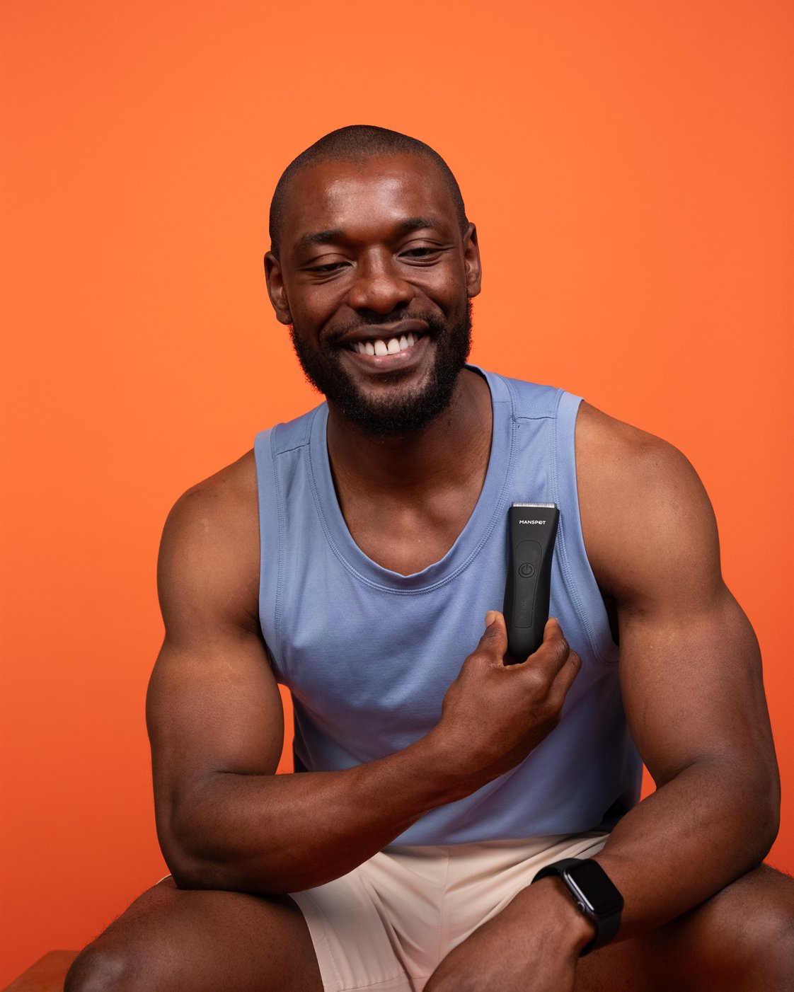 Smiling man holding a MANSPOT body trimmer before his grooming routine